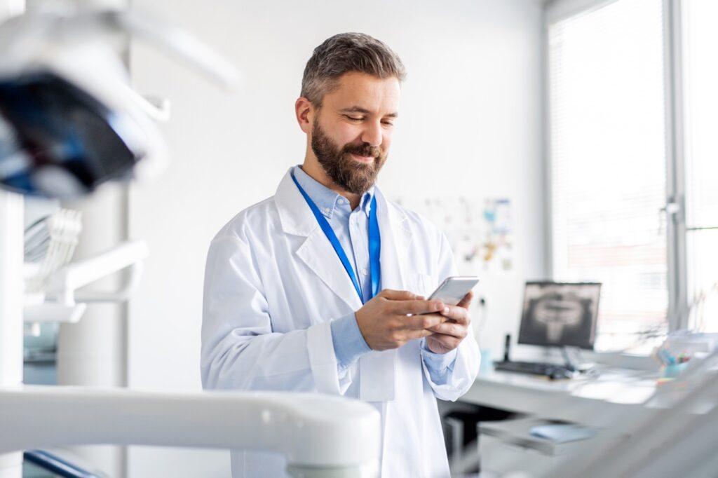 Immagine di un medico che sorride e tiene in mano un telefono